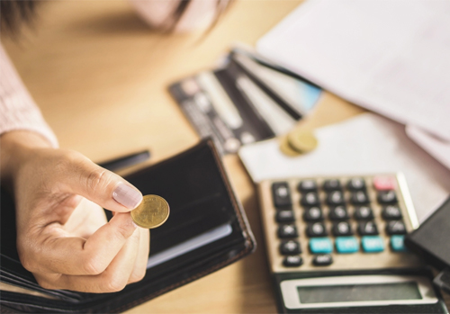 hand holding a coin near a calculator